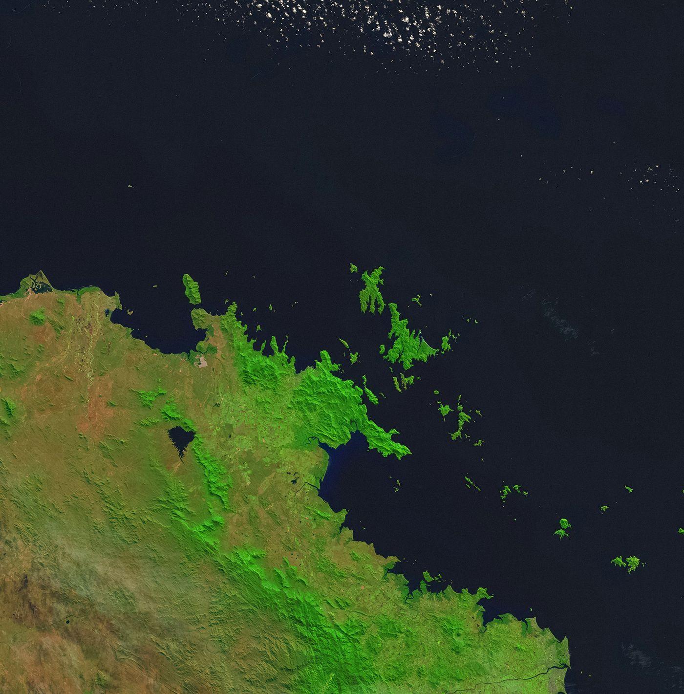 Satellite image of a green, forested coastline dotted with small islands